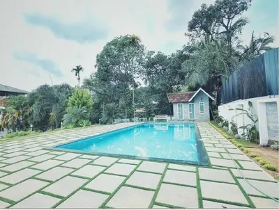 a swimming pool in front of a house at Wayanad Cliff Hotel Apartments in Kalpetta