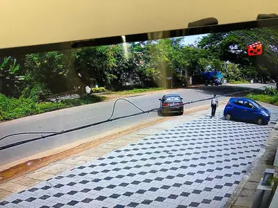 a man standing next to a blue car on a street at HOTEL JAAS CONTINENTAL in Edappāl