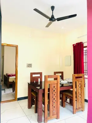 a dining room with a table and chairs and a ceiling fan at Edenvilla in Vālpārai