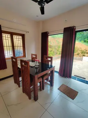 a dining room with a table and chairs and a window at Edenvilla in Vālpārai