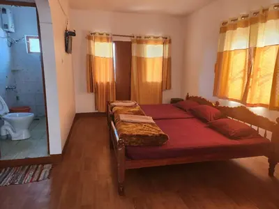 a bedroom with two beds and a bathroom with a mirror at Belair cottages in Kotagiri