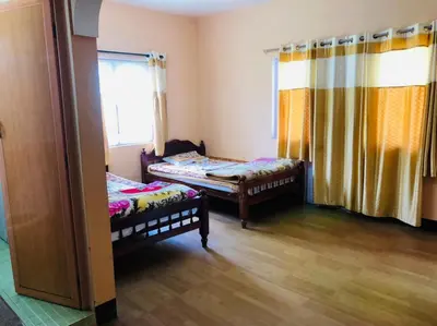 a room with two beds and a window at Belair cottages in Kotagiri
