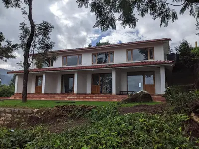 a white house with a tree in front of it at Moksha at Infinity Valley in Kotagiri