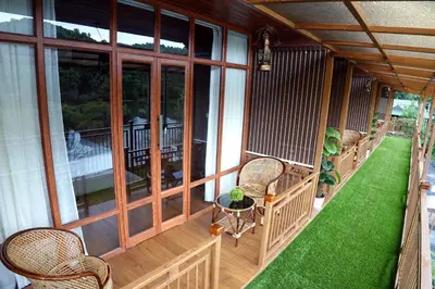 a screened in porch with chairs and a table at Mazhavilkadu ForestResort & Restaurant in Kozhikode