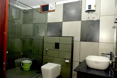 a bathroom with a toilet and a sink and a shower at ARAKKAL GUESTHOUSE in Kalpetta