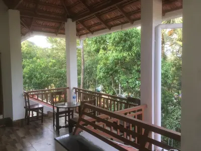 a balcony of a house with a table and chairs at Shilpa Vikas Homestay in Madikeri