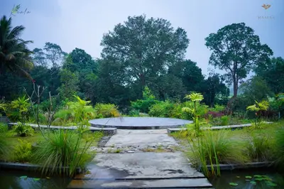a park with a bench in the middle of a garden at Maayaa riverside villa by KPM Tripenta in Attappādi