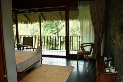 a bedroom with a bed and a balcony at Maayaa riverside villa by KPM Tripenta in Attappādi