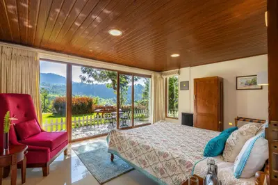 a bedroom with a bed and a chair and a window at amã Stays & Trails - Werifesteria, Coonoor in Coonoor