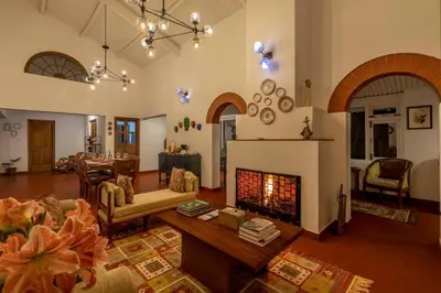 a living room with a fireplace and a table at amã Stays & Trails - Aberdeen, Coonoor in Wellington Town