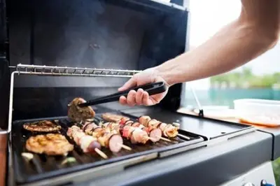 a person cooking food on a grill with a spatula at amã Stays & Trails - Aberdeen, Coonoor in Wellington Town