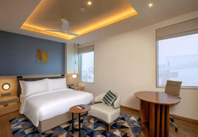 a bedroom with a bed and a desk and a table at O by Tamara Coimbatore in Coimbatore
