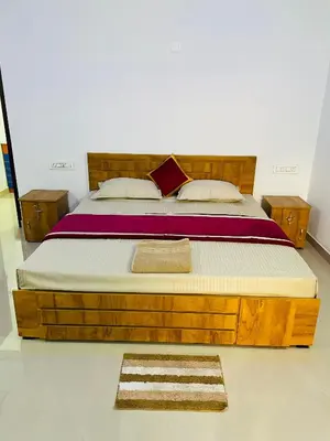 a bed with a wooden frame in a room at Flowers Villa in Ambalavayal