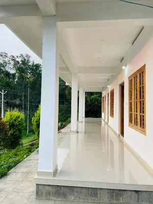 an empty corridor of a white building with columns at Flowers Villa in Ambalavayal