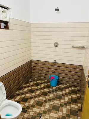 a bathroom with a toilet and a blue bucket at Flowers Villa in Ambalavayal
