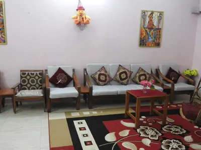 a living room with couches and pillows at Shanthi Villa in Coonoor