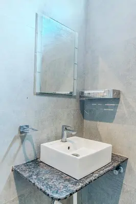 a bathroom with a white sink and a mirror at Kaadgal Resort in Kanakapura