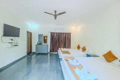 a living room with two beds and a flat screen tv at Kaadgal Resort in Kanakapura