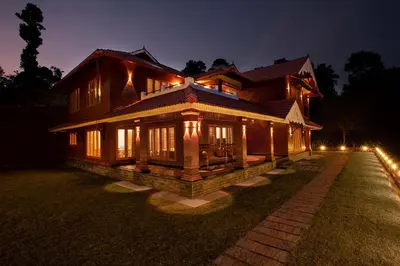 a large wooden house at night with lights at StayVista at Regal Retreat 5BR - Big Villa with Pvt Pool in Wayanad