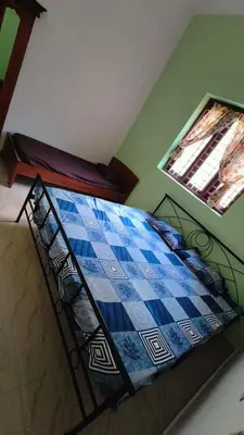a bedroom with a bed with a blue and white blanket at Dragster Homes in Kizhake Chālakudi