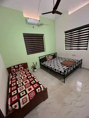 two beds in a room with green walls at Dragster Homes in Kizhake Chālakudi
