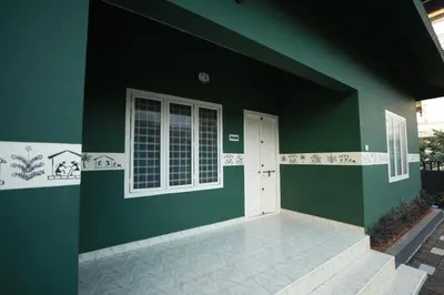 a green and white house with a white door at San Unik Homestay in Nilambūr