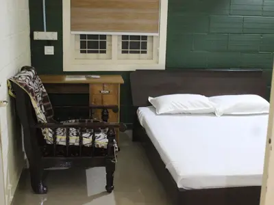 a bedroom with two beds and a desk and a window at San Unik Homestay in Nilambūr