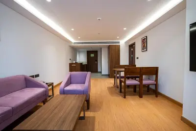 a living room with a couch and a table and chairs at Lilac Hotel Guruvayur in Guruvāyūr