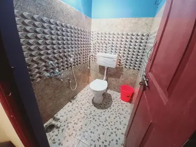 a bathroom with a toilet and a red door at Nature Greens Cottage in Madikeri