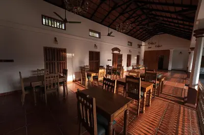 a dining room with wooden tables and chairs at Meleppura Heritage Homestay in Chāvakkād