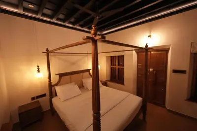 a bedroom with a canopy bed with white sheets at Meleppura Heritage Homestay in Chāvakkād