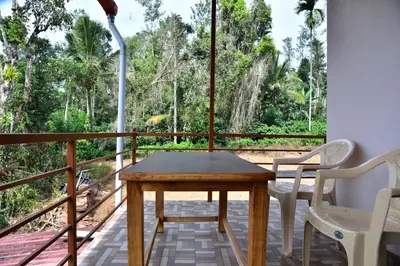 a room with a table and chairs on a balcony at Madhuvana Homestay Coorg in Madikeri