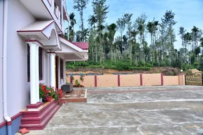 a white building with flowers on the porch at Madhuvana Homestay Coorg in Madikeri