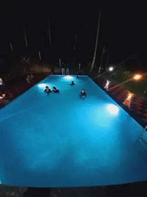 a group of people laying on top of a swimming pool at night at Elora Resort Wayanad in Kalpetta