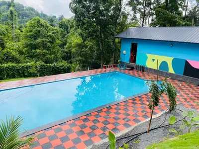 a swimming pool in front of a house at Elora Resort Wayanad in Kalpetta