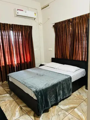 a bedroom with a bed with red curtains at ZAHIR RESIDENCY in Kondotti