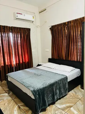 a bedroom with a bed with red curtains at ZAHIR RESIDENCY in Kondotti