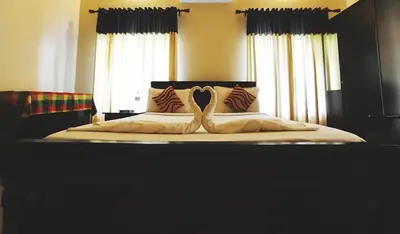 a bed with two swans shaped pillows on it at Dreamnest Residency in Kalpetta