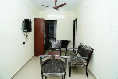 a room with chairs and a table and a ceiling fan at Meadow Comfort Stay in Coimbatore