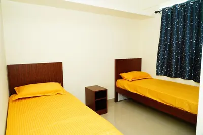 a bedroom with two beds and a blue curtain at Meadow Comfort Stay in Coimbatore