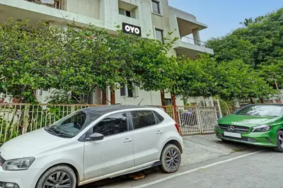 two cars parked in a parking lot in front of a building at Super Hotel O Indra Suites in Mysore