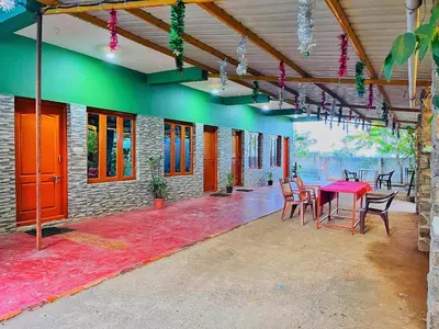 a patio with a red table and chairs in a building at SPM Residency, From Live2Travel Group. in Masinagudi