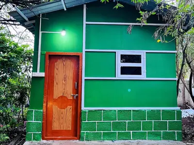 a green house with a door and a window at SPM Residency, From Live2Travel Group. in Masinagudi