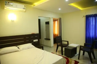 a bedroom with a bed and chairs and a mirror at City Tower Lodge in Nilambūr