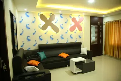a living room with a black couch andcolored crosses on the wall at City Tower Lodge in Nilambūr