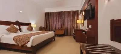 a hotel room with a bed and a television at ASHOKA INN in Trichūr