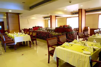a restaurant with tables and chairs with yellow tablecloths at ASHOKA INN in Trichūr