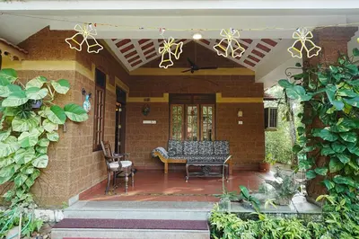 a porch of a house with a bench and chairs at Sukrutham Farmstay in Trichūr