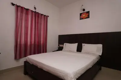 a bedroom with a large bed with a red curtain at KV Residency in Coimbatore