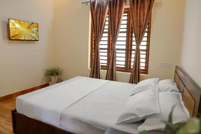a bedroom with a white bed with a window at CELESTIAL HOMESTAY in Pinangode
